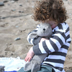 A child cuddling the small grey cuddly Senger seal.