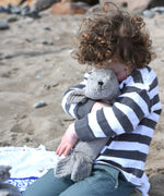 A child cuddling the small grey cuddly Senger seal.