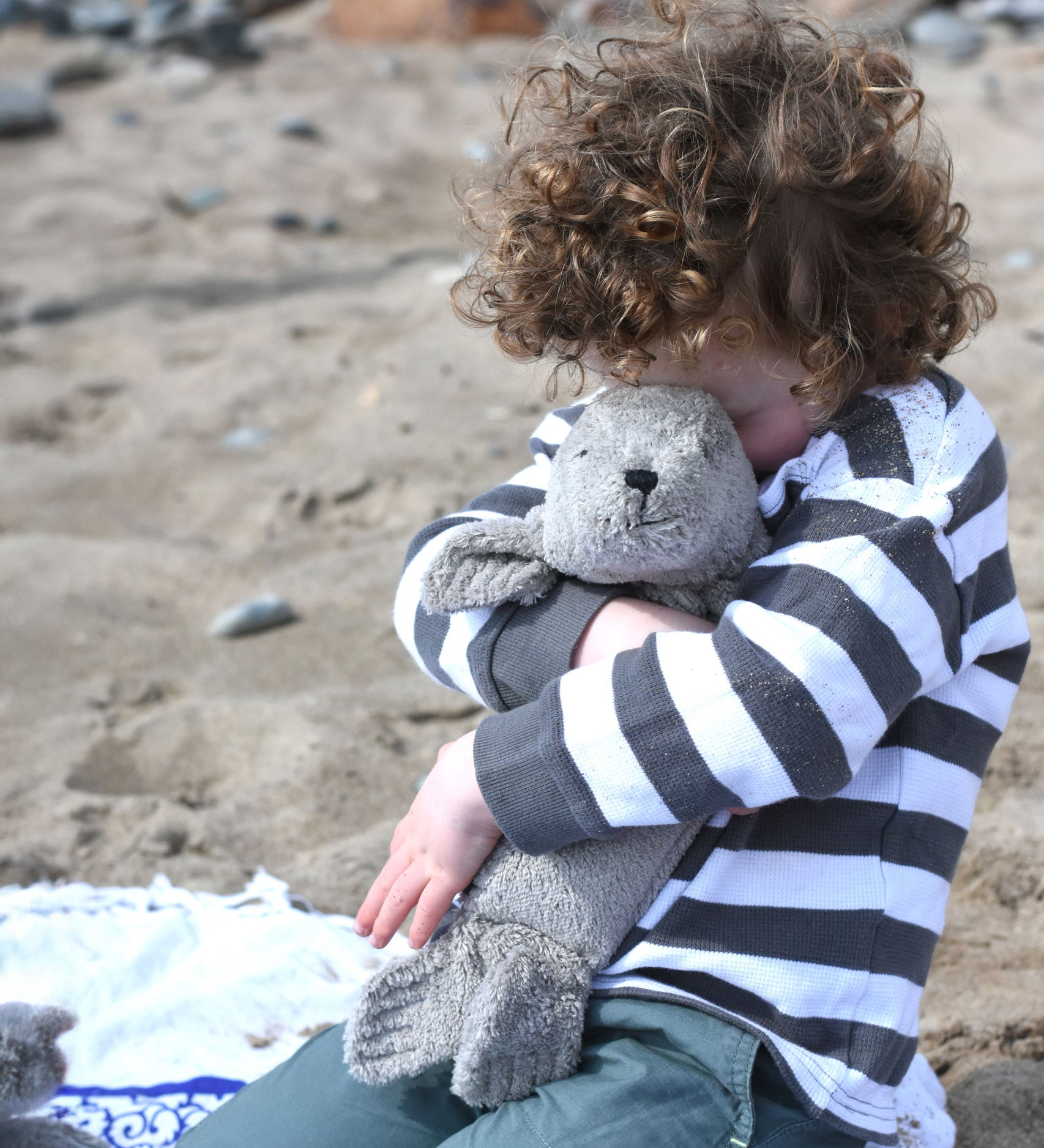 A child cuddling the small grey cuddly Senger seal.