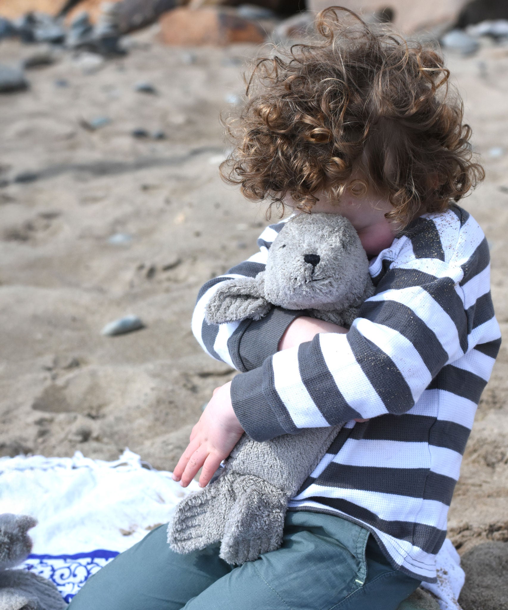 A child cuddling the small grey cuddly Senger seal.