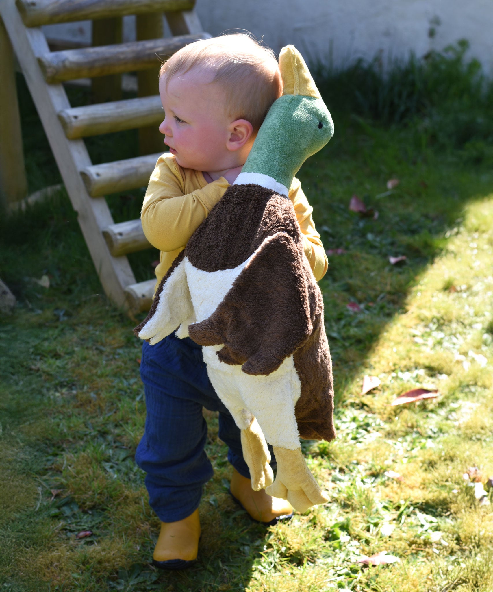 A young child carrying a Senger Large Cuddly Drake Duck soft toy.