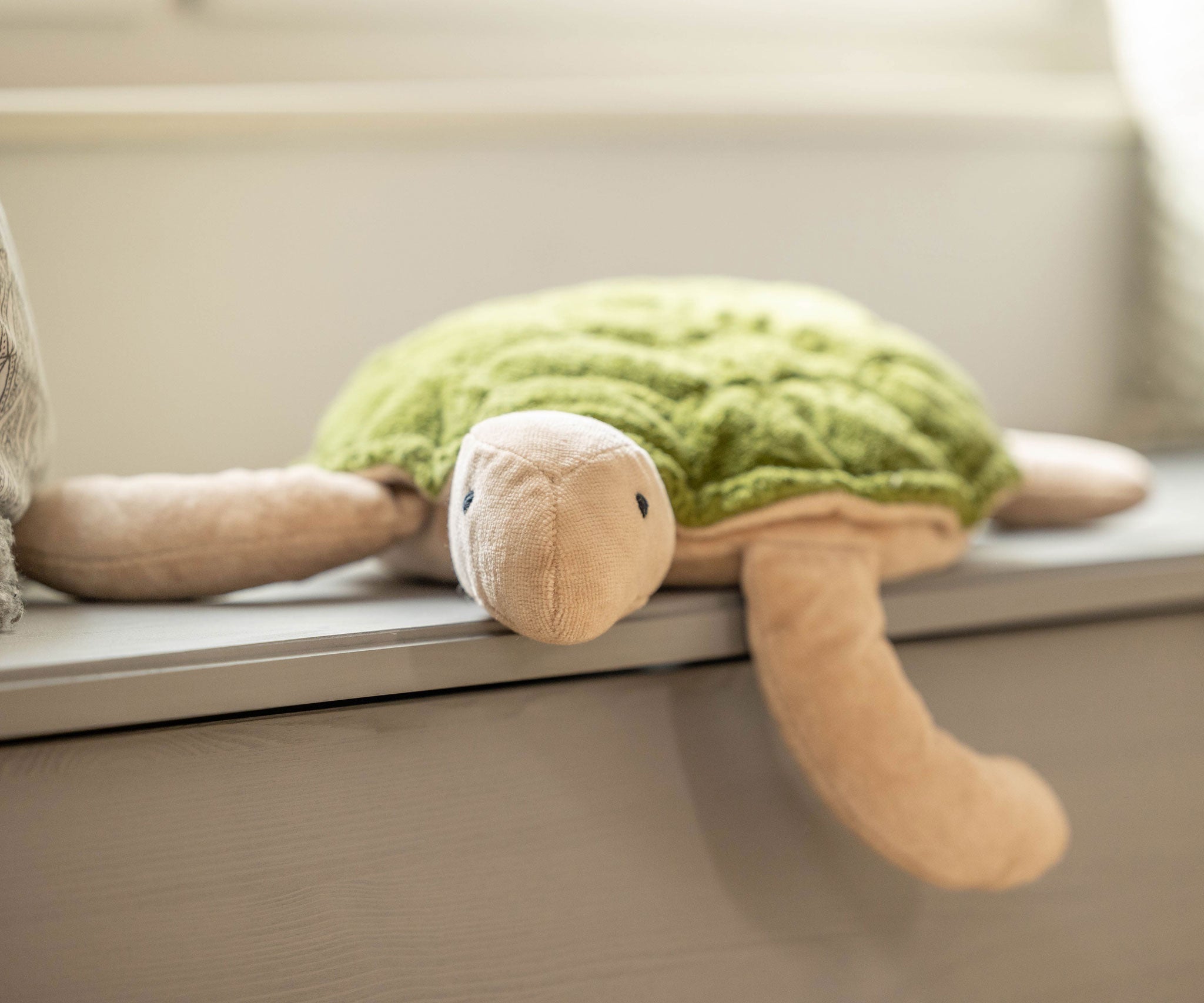 A large Senger Cuddly Green Turtle placed on a window sill. 