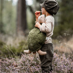 A child standing in a wooded area holding a large cuddly Senger Turtle soft toy. 
