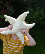 A child holding up a small Senger starfish cuddly toy in front of his face. The Senger soft toys are made from organic materials and natural fillings.