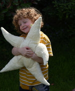A child cuddling the large Senger starfish soft toy, the child's arms are wrapped around the starfish holding it close. The Senger starfish are part of a wide range of organic soft toys available here at babipur.