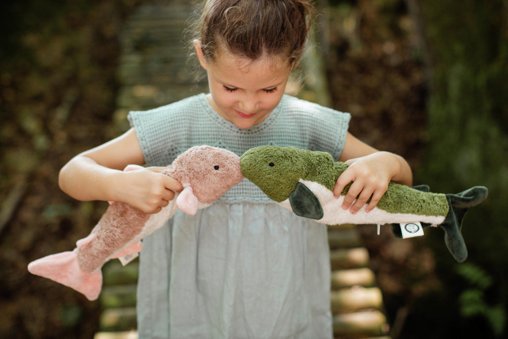 A little girls playing with two Senger cuddly fish organic stuffed toys