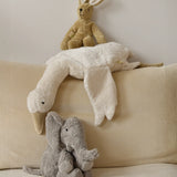 A large Senger elephant cuddly toy with a white goose and beige rabbit soft toy lying above on a corduroy cushion