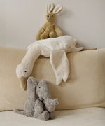 A large Senger elephant cuddly toy with a white goose and beige rabbit soft toy lying above on a corduroy cushion