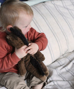 A close up of a child cuddling the Senger small brown floppy horse soft toy. This brown horse is from the Senger Floppy collection, a range of soft toy animals made from organic and natural materials. 