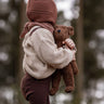 A toddler in the forest, holding the Senger organic cotton stuffed toy brown teddy bear