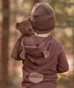 A toddler in the forest, holding the Senger organic cotton stuffed toy brown teddy bear