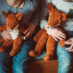A close up of two children's hands holding Senger Floppy Foxes.