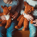 A close up of two children's hands holding Senger Floppy Foxes.