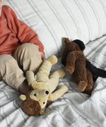 Two Senger soft toys placed on a cream and black striped duvet, a hedgehog and horse from Senger's floppy collection of soft toys made with organic cotton and natural fillings. A young child can be seen in the background.