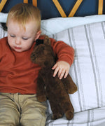 A child holding the Senger brown floppy horse under their arm. This brown horse is from the Senger Floppy collection, a range of soft toy animals made from organic and natural materials. 