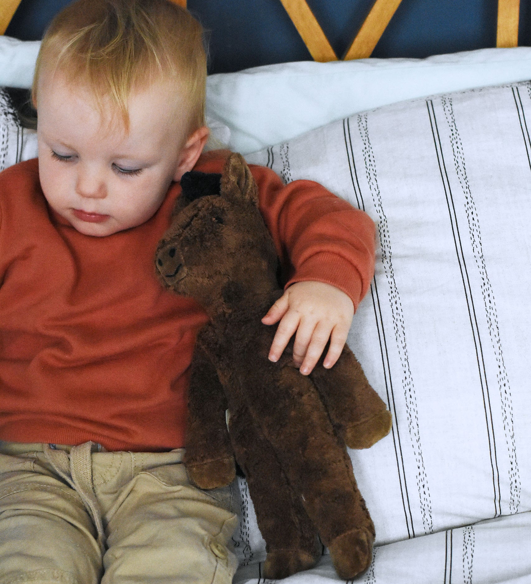 A child holding the Senger brown floppy horse under their arm. This brown horse is from the Senger Floppy collection, a range of soft toy animals made from organic and natural materials. 