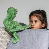Child with a hand in a Senger GOTS organic cotton green frog puppet standing behind a sofa
