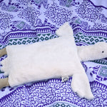 A Senger white organic cotton goose pillow placed on a blue and white patterned blanket. 