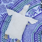 A Senger white organic cotton goose pillow placed on a blue and white patterned blanket. 