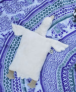 A Senger white organic cotton goose pillow placed on a blue and white patterned blanket. 