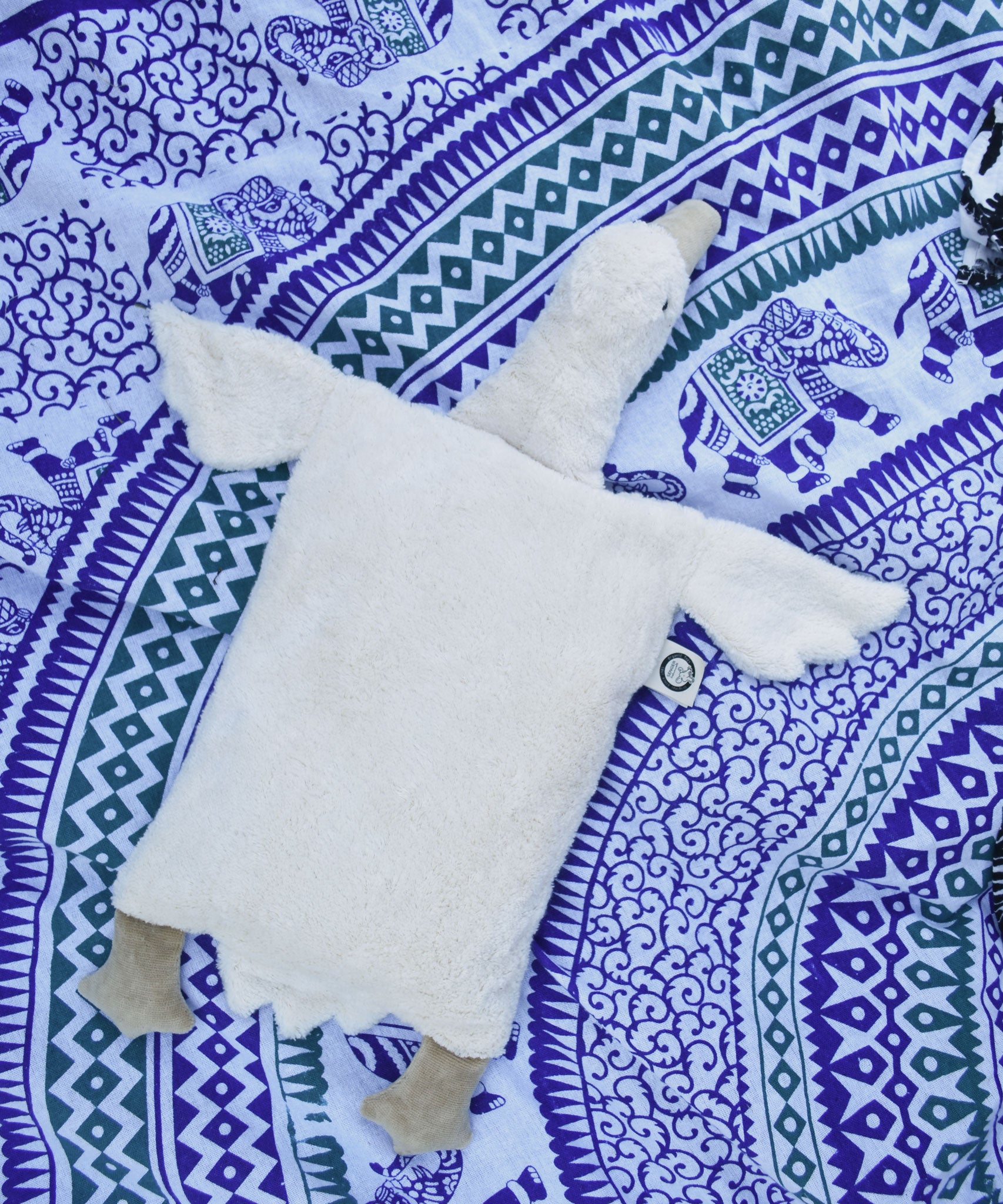 A Senger white organic cotton goose pillow placed on a blue and white patterned blanket. 