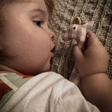 Senger giraffe grasping toy held closely by a child showing the pink and white check design on organic cotton fabric