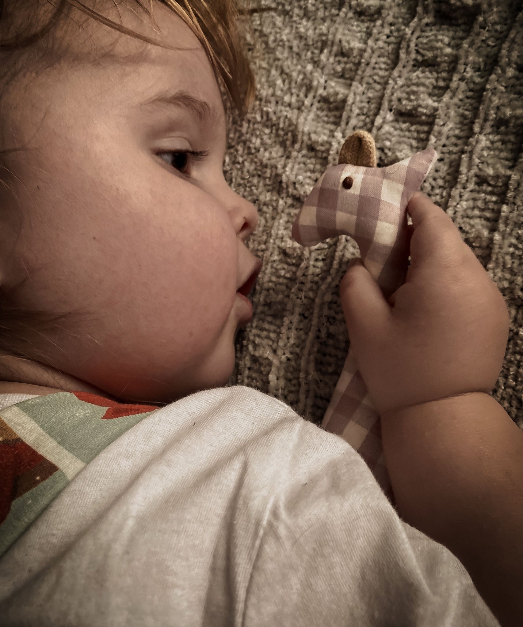 Senger giraffe grasping toy held closely by a child showing the pink and white check design on organic cotton fabric