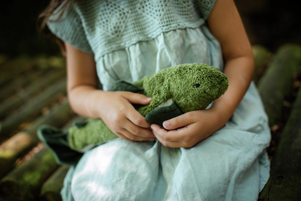 A closeup of a little girl cradling a Senger organic cotton cuddly stuffed fish toy