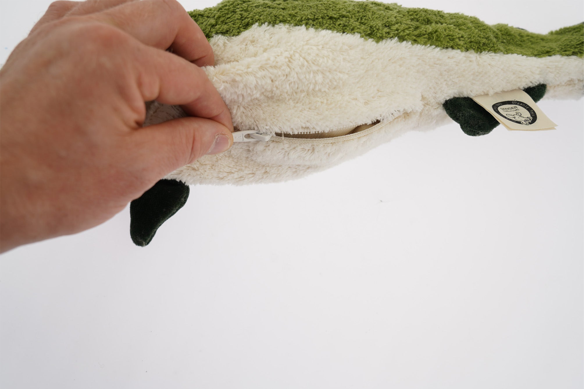 A hand unzipping the organic cotton Senger green fish cuddly toy
