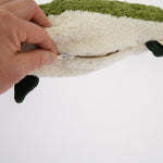A hand unzipping the organic cotton Senger green fish cuddly toy