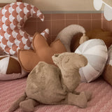 A large Senger camel cuddly soft toy standing on a blanket with cushions in the background