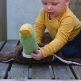 A child sitting on wooden plank holding up the Senger Large Cuddly Drake Duck soft toy's neck.