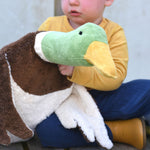 A close up of the Senger Large Cuddly Drake Duck soft toy in a child's hands.