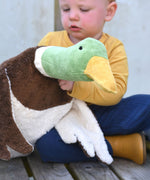A close up of the Senger Large Cuddly Drake Duck soft toy in a child's hands.