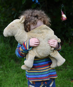 A child cuddling a large Senger Cuddly Camel Organic Heatable Soft Toy. The large camel soft toy is part of a wide selection of soft toys made from organic cotton and natural fillings available at Babipur.