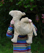 A child holding up the large Senger Cuddly Camel Organic Heatable Soft Toy. The child is wearing a striped rainbow coloured top. 