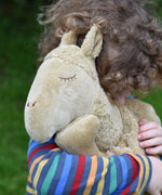 A close up of a child cuddling the large Senger Cuddly Camel Organic Heatable Soft Toy. The large camel soft toy is part of a wide selection of soft toys made from organic cotton and natural fillings available at Babipur.