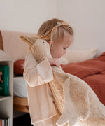 Child holding a large cream Senger cuddly goose soft toy in a bedroom