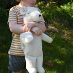 A child cuddling the Senger large cuddly polar bear soft toy in their arms.