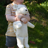 A child cuddling the Senger large cuddly polar bear soft toy in their arms.
