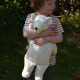 A child cuddling the Senger large cuddly polar bear soft toy in their arms.