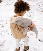Child carrying a large Senger grey cuddly soft toy in the snow