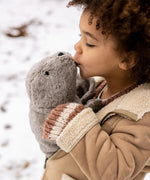 Child holding and kissing a large Senger grey cuddly soft toy in the snow