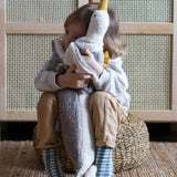 Child hugging a large Senger dolphin and seagul cuddly toys and sitting on a woven cushion