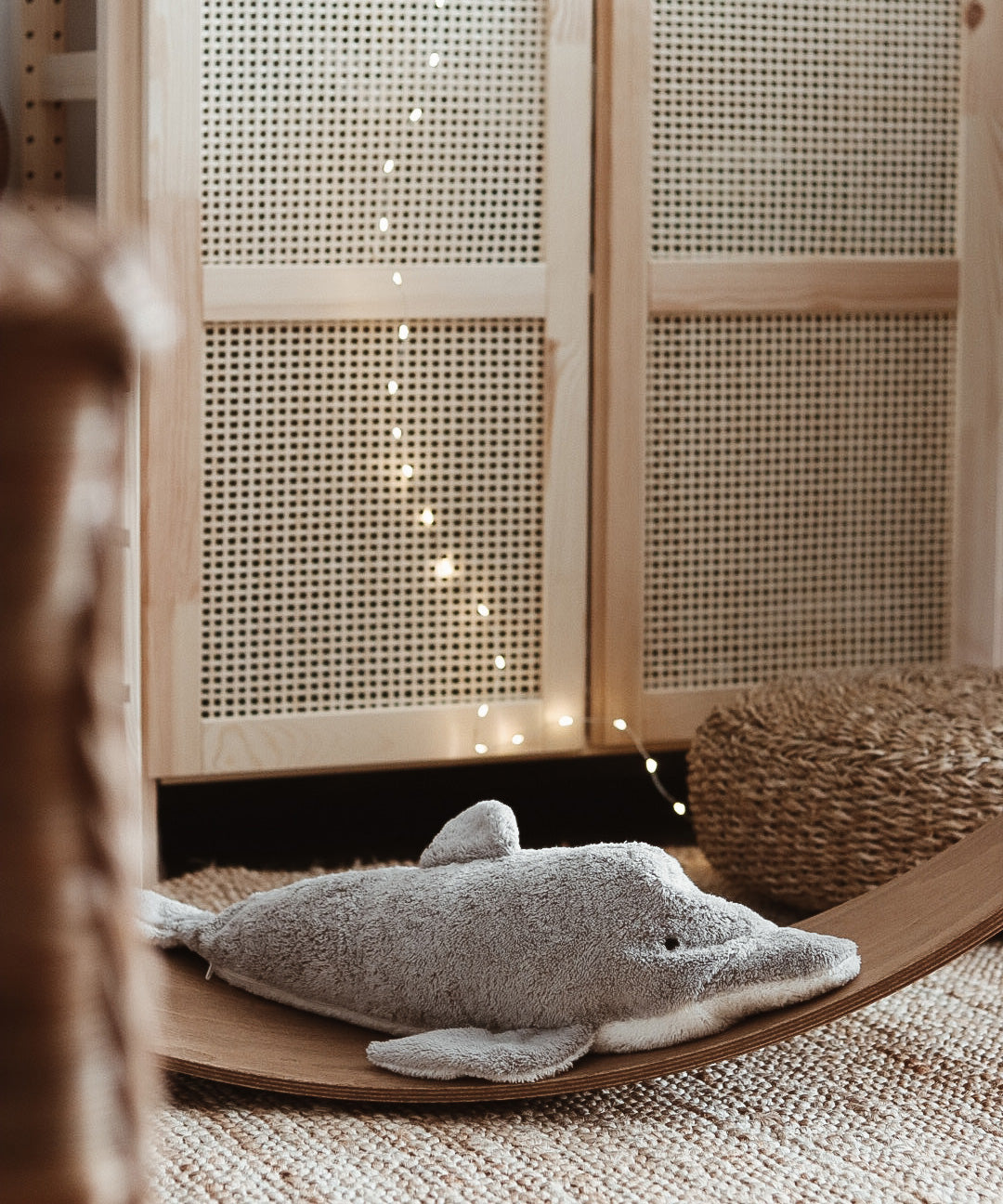 A Senger large organic cotton stuffed dolphin toy on a Wobbel board in a play room nursey