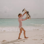 A little girl playing with the Senger large organic cotton stuffed dolphin toy on the beach