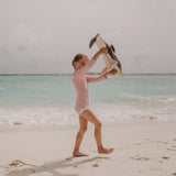 A little girl playing with the Senger large organic cotton stuffed dolphin toy on the beach