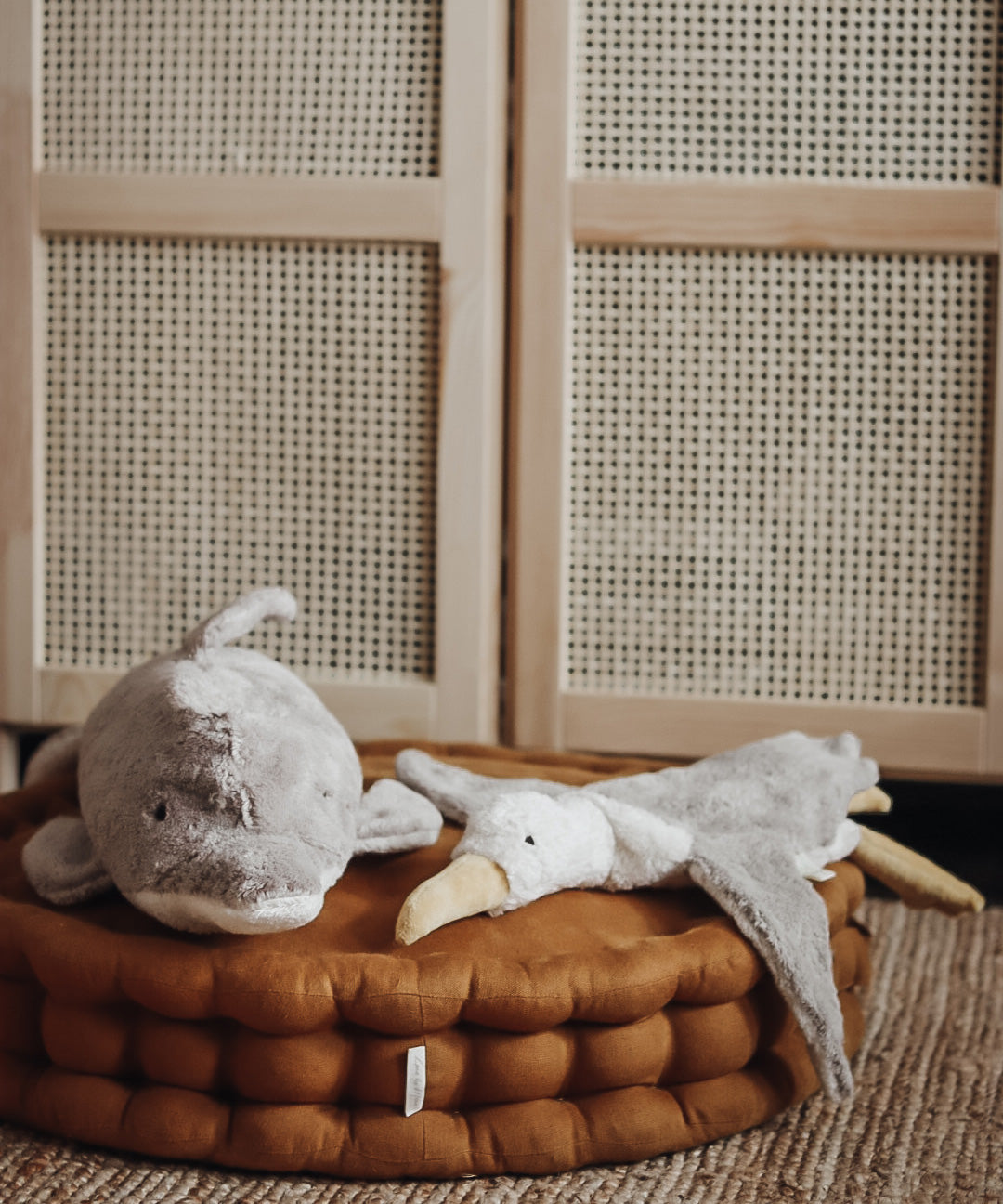 A Senger large organic cotton stuffed dolphin toy and a seagull toy on a cushion