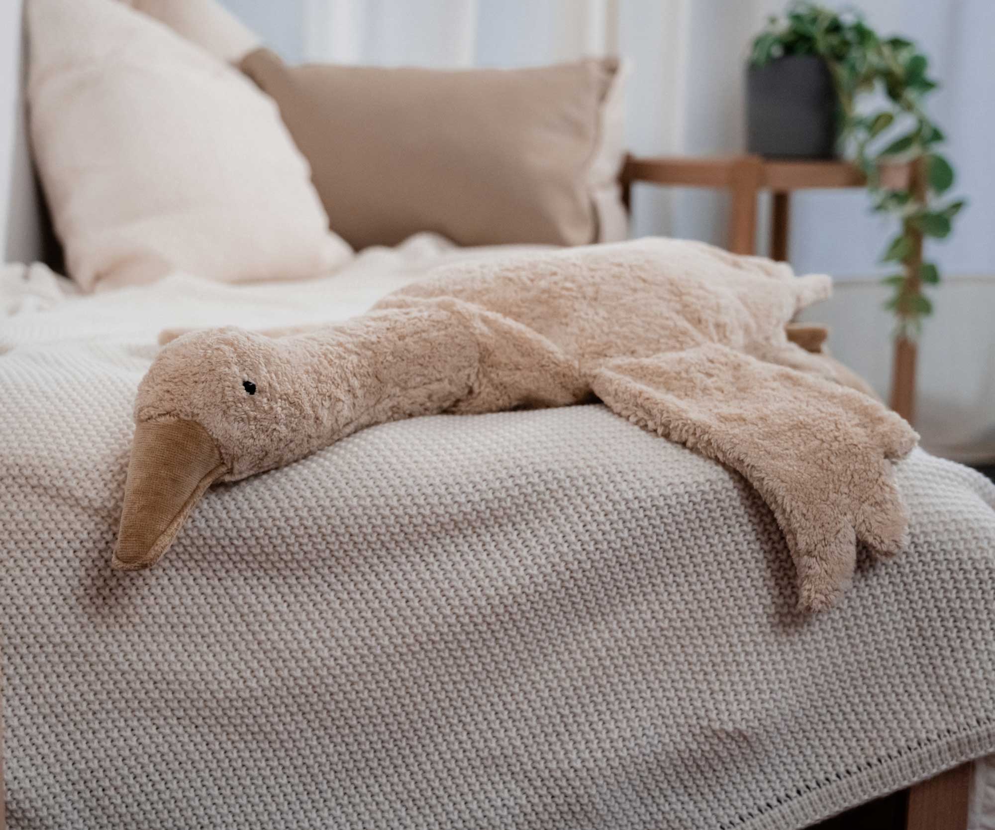 A Cuddly Goose organic soft toy in a creamy Linen colour placed on a sofa on a beige blanket. These soft toys are created from the highest quality, sustainable and traceable natural materials. Senger cuddly animal toys and soft dolls are handmade in Germany with love and attention to detail and we are proud Senger stockists here at Babipur. 