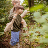 Two children walking in a forest, one is holding a Senger Large Cuddly Goose organic soft toy in a creamy Linen colour. The other child has the smaller version of the goose. These soft toys are created from the highest quality, sustainable and traceable natural materials. Senger cuddly animal toys and soft dolls are handmade in Germany with love and attention to detail and we are proud Senger stockists here at Babipur. 